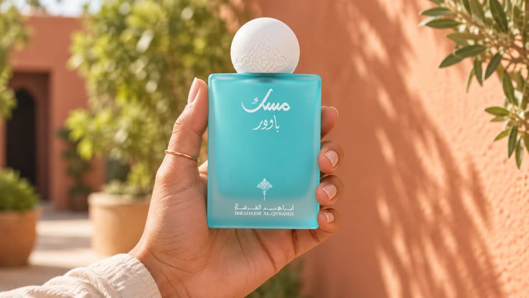 Une main tient le flacon turquoise Ibraq Powder Musk dans une cour ensoleillée.